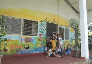 Grupo de niños estudiantes sonriendo frente al nuevo mural terminado de su colegio en Jamundí.