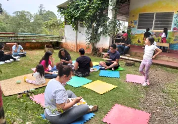 Familias compartiendo un picnic sobre tapetes de colores en las zonas verdes de la escuela tras la actividad de pintura.